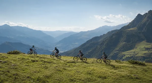 Ciclistas en una travesía MTB y eBike por etapas con valle y montañas al fondo.